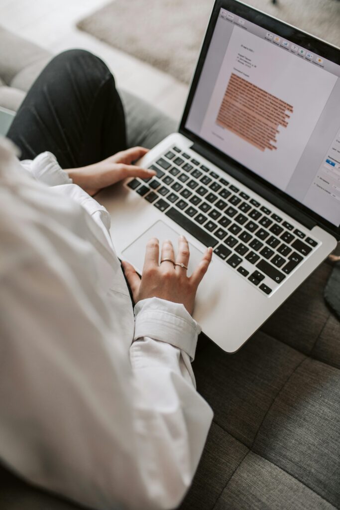 Woman working on a laptop indoors, focusing on document editing and remote work.